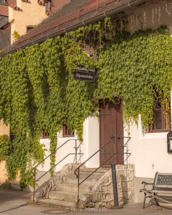 Alpenstube met planten die boven de ingang hangen 