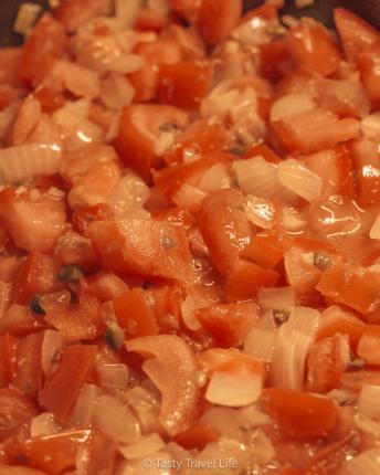 verse pastasaus in een pan. Tomaten, kappertjes, ui en knoflook. 