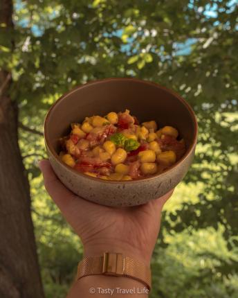 fresh pasta with fresh pasta sauce in a bowl. It is hold in front of a tree.