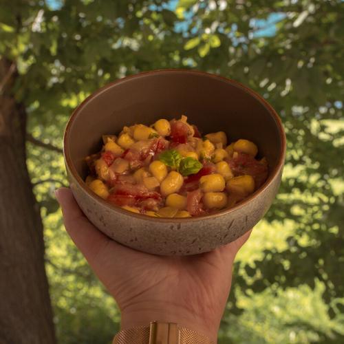 fresh pasta with fresh pasta sauce in a bowl. It is hold in front of a tree.