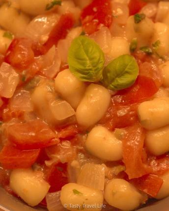 close-up van de pasta met pastasaus. Twee basilicumblaadjes erop. 