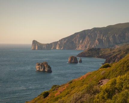 Sardinia coast line with rough cliffs and green bushes. 